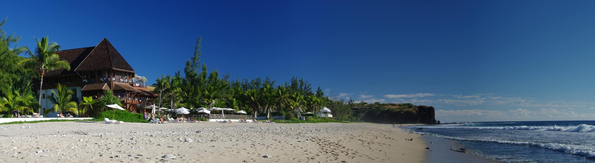 La plage de sable blanc de Boucan Canot, son front de mer et le cap volcanique.