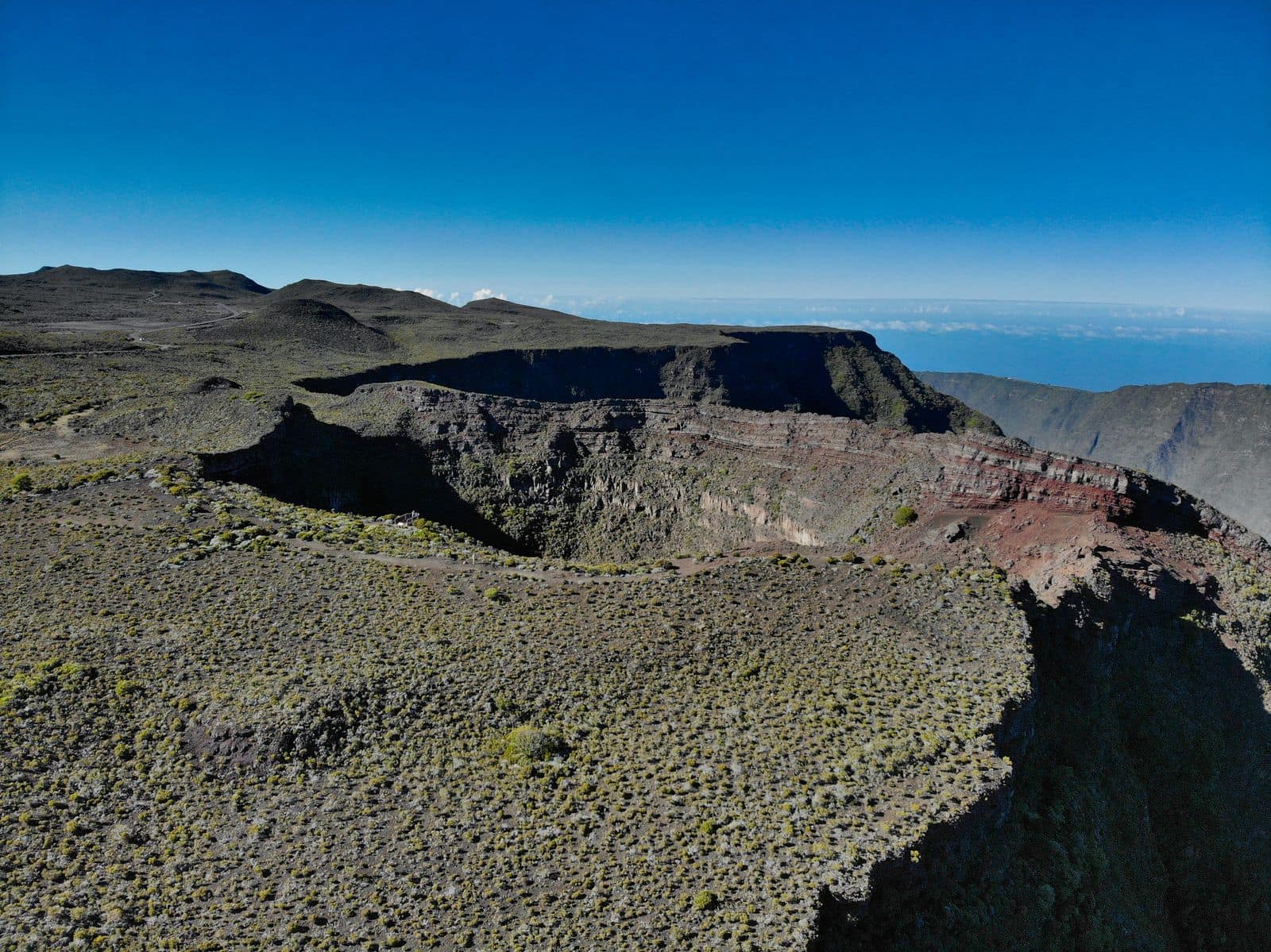 Vue aérienne d'un cratère du massif de la Fournaise, remparts stratifiés ocre et rouge