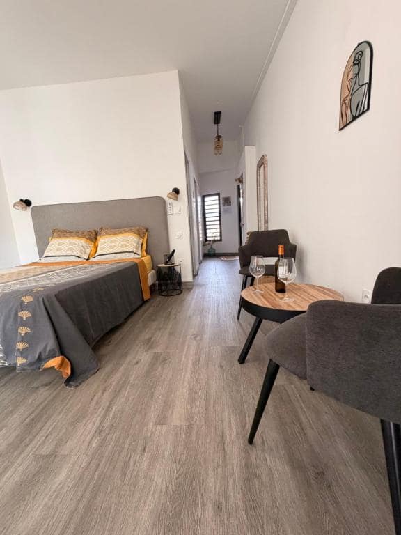 Autre angle de la chambre avec coin bureau et bouteille de vin · © ATÈRLA