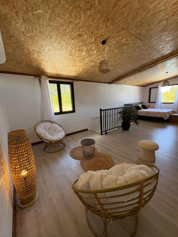 Mezzanine à fauteuils papasan rotin, ouverte sur la chambre en fond · © Au Pied des Sources by K