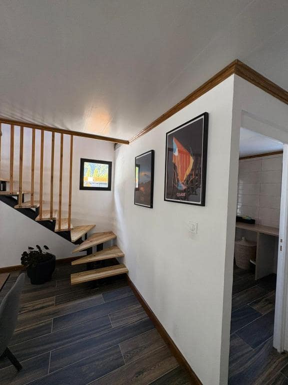 Escalier bois qui descend au niveau bas, affiches Cilaos au mur · © Au Pied des Sources by K