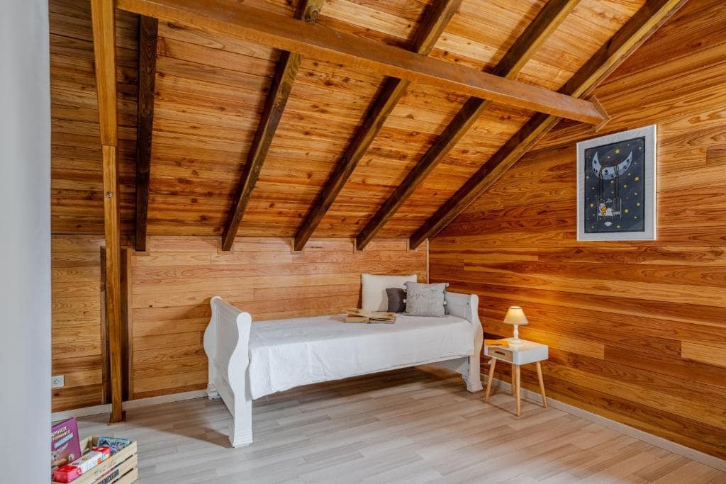 Chambre mansardée, petit lit blanc sous charpente en bois · © Barbadine974