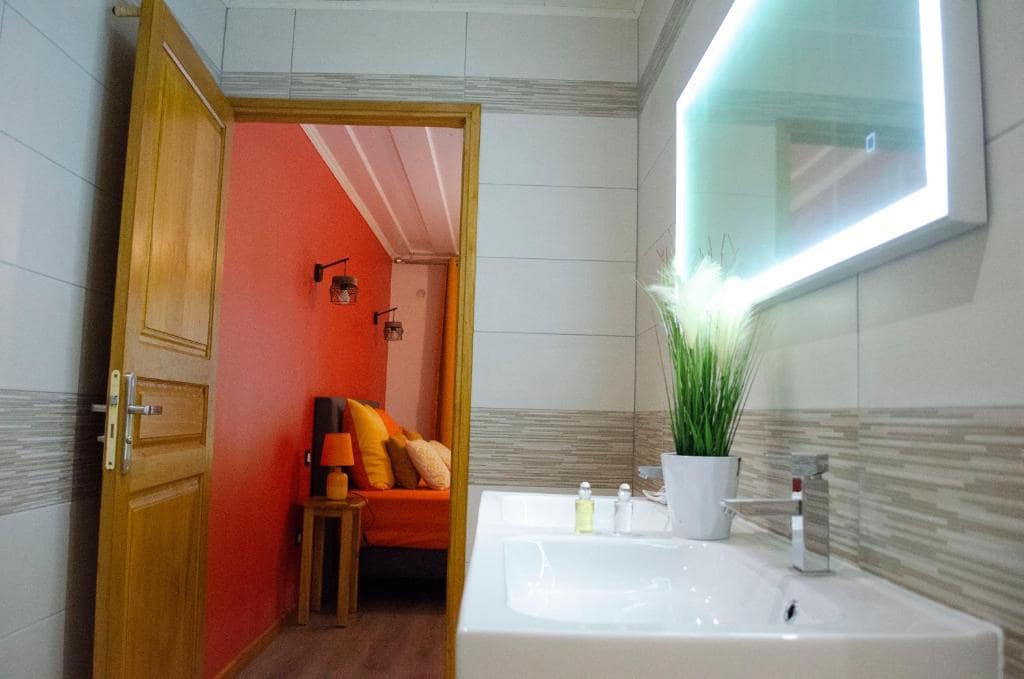 Salle d'eau, vasque et miroir rétroéclairé, ouverture sur la chambre orange · © Bec Roz'