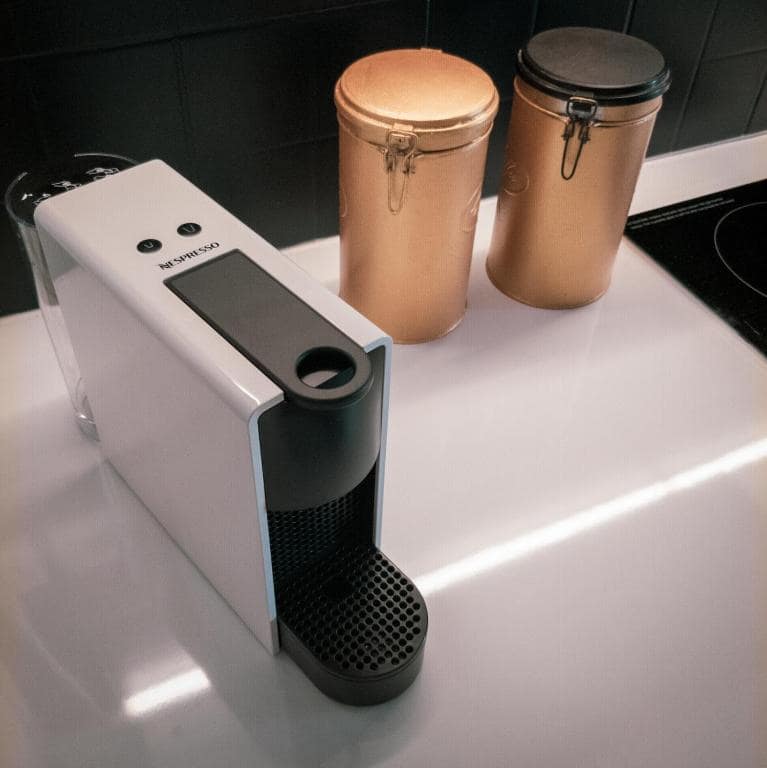 Machine Nespresso et boîtes cuivrées sur le bar cuisine · © Bleu Nuit