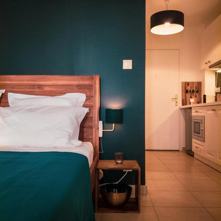 Autre angle sur le lit, cuisine ouverte visible en fond · © Bleu Nuit