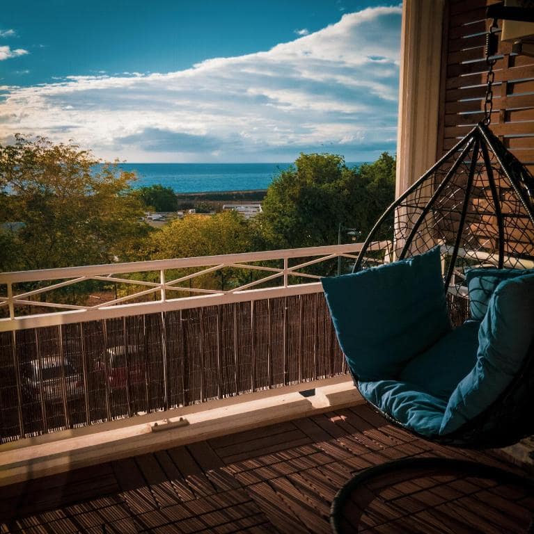 Balcon en plan large, vue océan et rambarde blanche · © Bleu Nuit