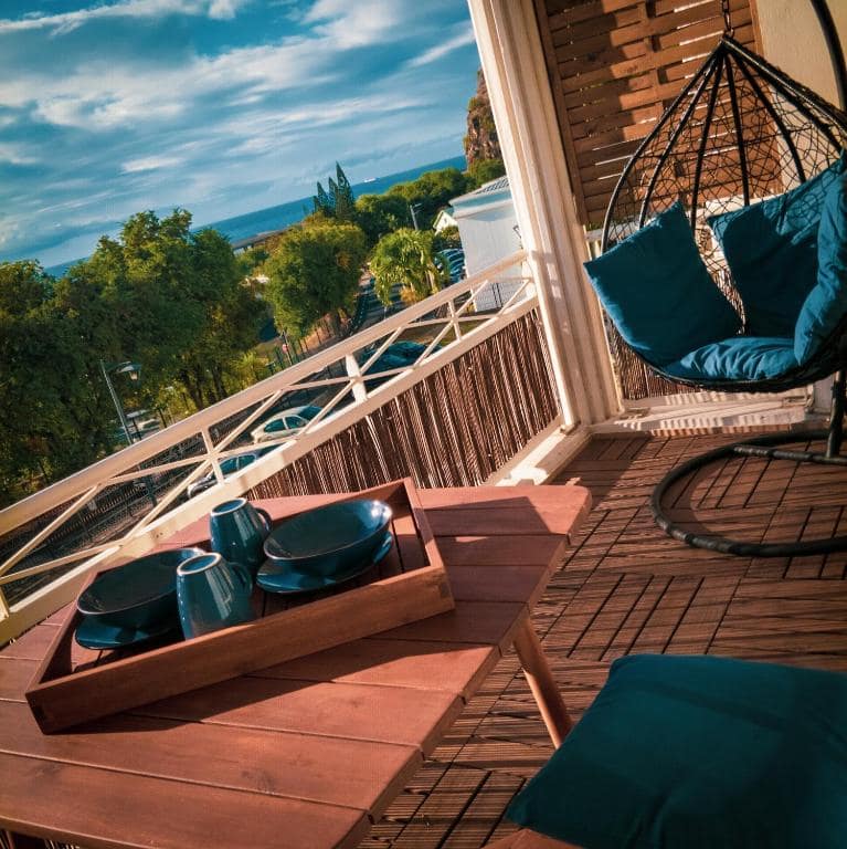 Balcon vue mer, fauteuil suspendu, plateau matin · © Bleu Nuit