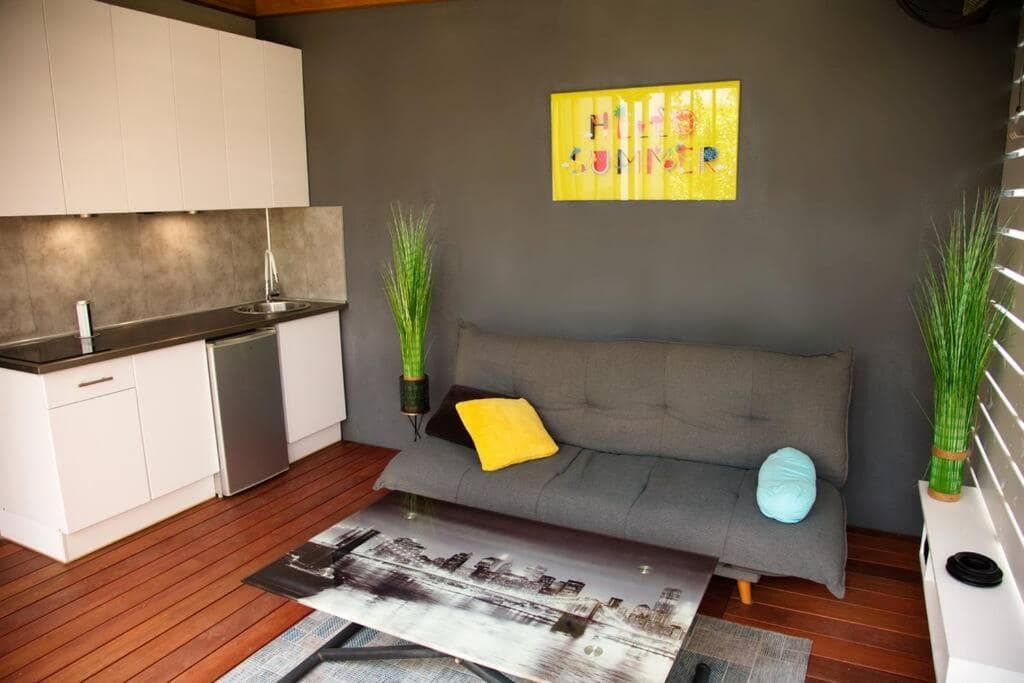 Coin salon avec canapé et kitchenette blanche · © Les Songes