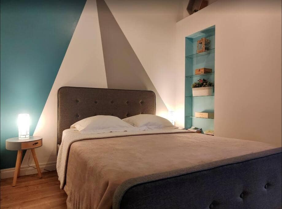 Chambre à tête matelassée grise, mur en triangle bicolore · © Les Songes