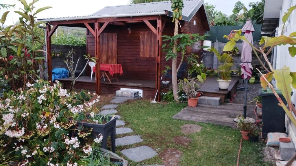 Kiosque en bois planté d'un papayer, jardin fleuri autour · © Bungalow Maïdo