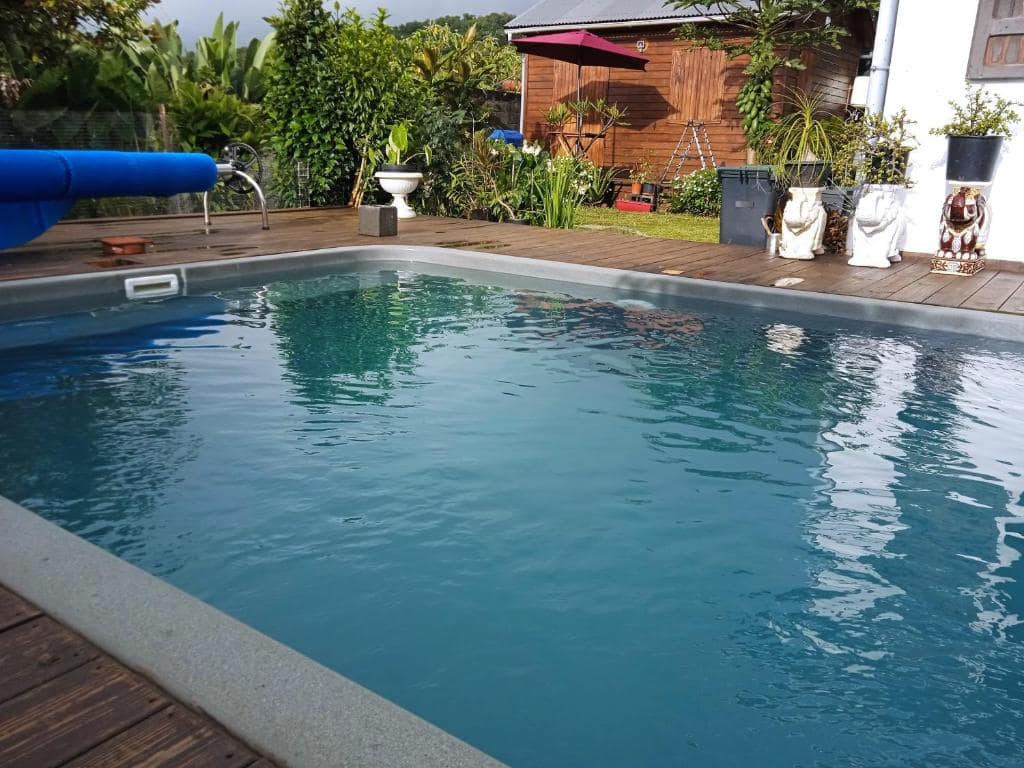 Piscine privée devant le bungalow bois et parasol rouge · © Bungalow Maïdo
