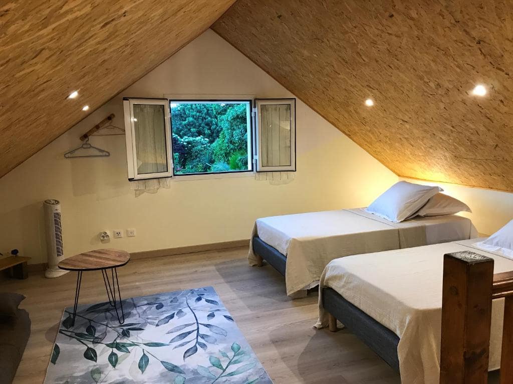 Chambre carrelée avec couvre-lit à pois et miroir mural éléphants · © La Case Floria