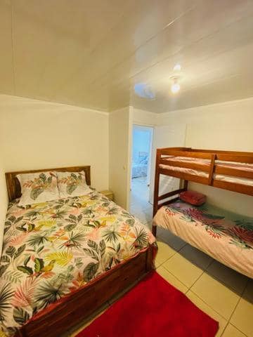 Chambre avec lit double et lits superposés, décor tropical · © Case Vi d'O