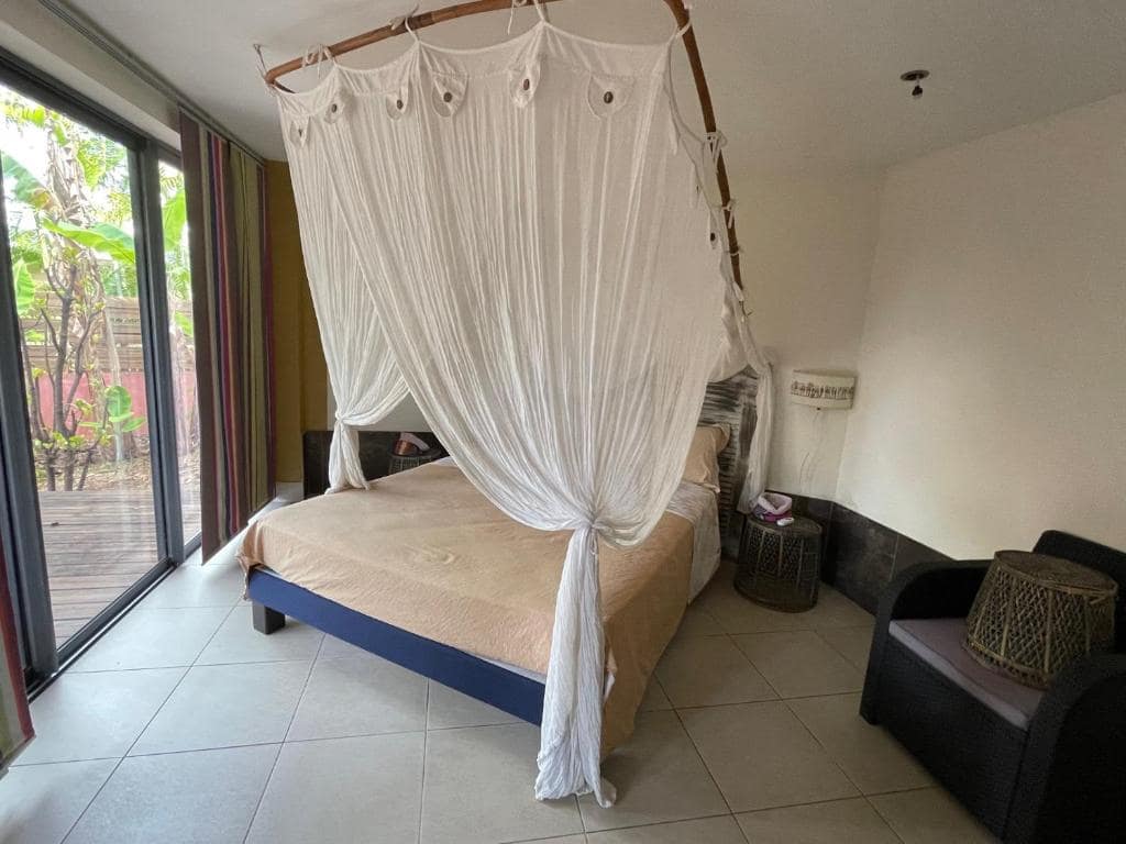 Chambre avec lit à baldaquin et moustiquaire · © Caz Margouillat