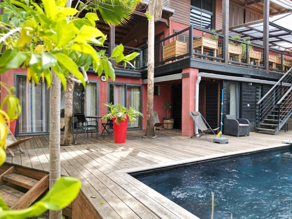 Terrasse en bois, palmier et coin salon en bord de piscine · © Caz Margouillat