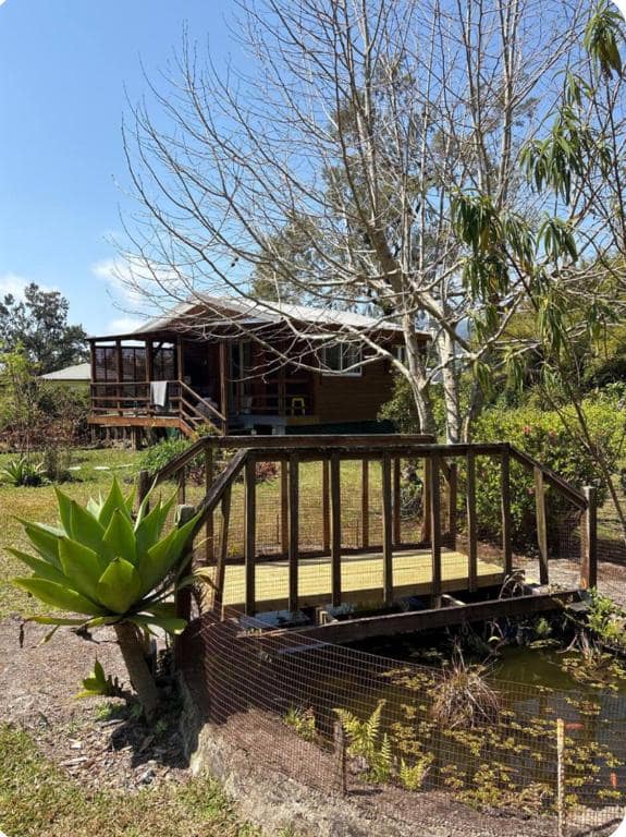Chalet sur pilotis avec passerelle bois et bassin en contrebas · © Chalets Medinilla