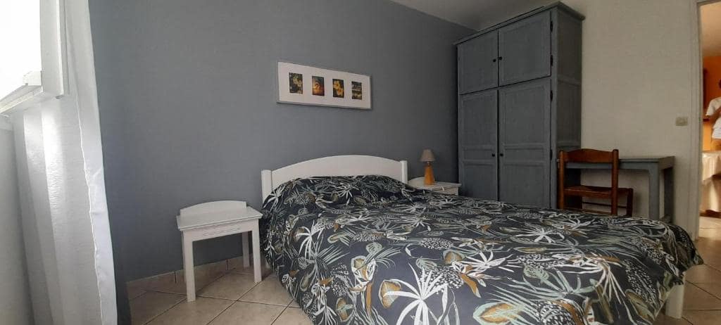 Chambre bleue avec lit habillé de motifs floraux et grande armoire penderie · © Chambre d'hôte Magdeleine