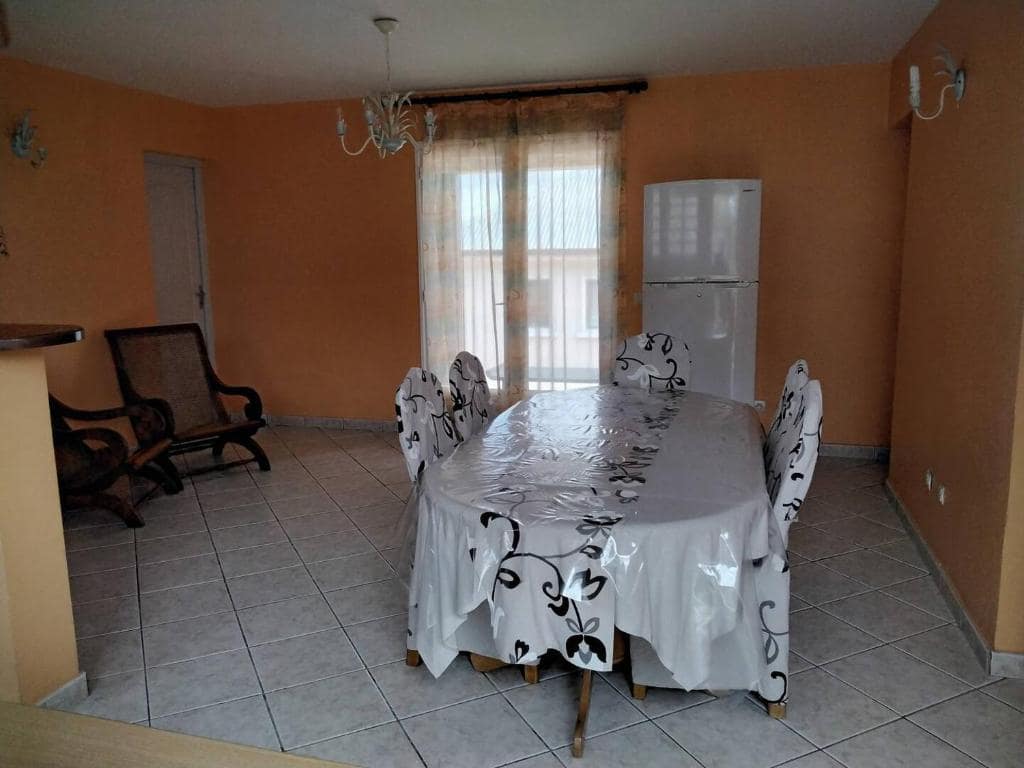Salle à manger avec chaises housse à motif et réfrigérateur en fond · © Chambre d'hôte Magdeleine