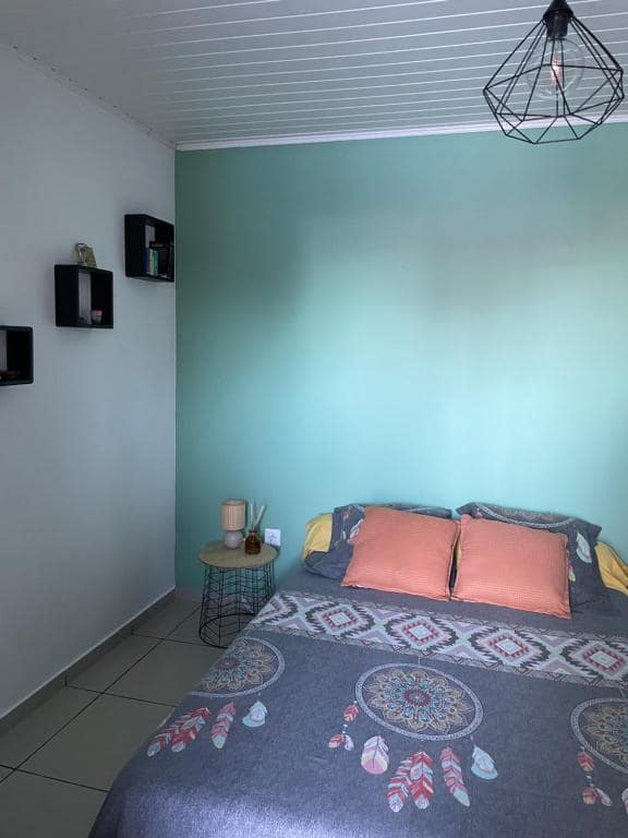 Chambre au mur vert d'eau avec coussins corail et table d'appoint · © Chambre dans notre Villa avec Piscine