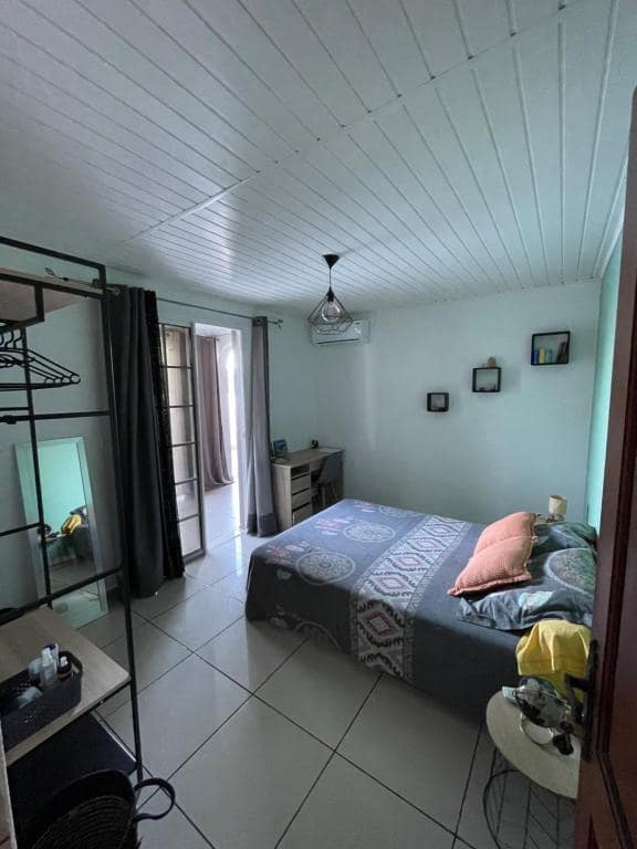 Chambre carrelée, lit à coussins corail, bureau au fond · © Villa piscine