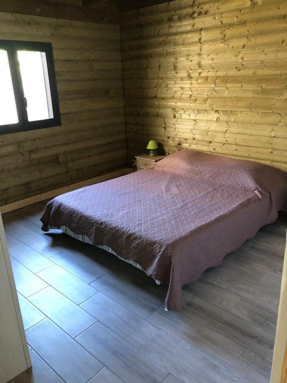 Chambre lambrissée bois, lit double couvre-lit prune · © Chez Paulette