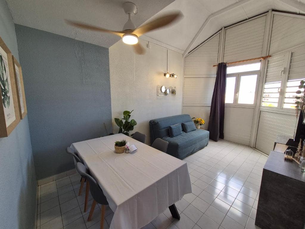 Séjour côté véranda à jalousies, ventilateur de plafond · © Cœur Citadin