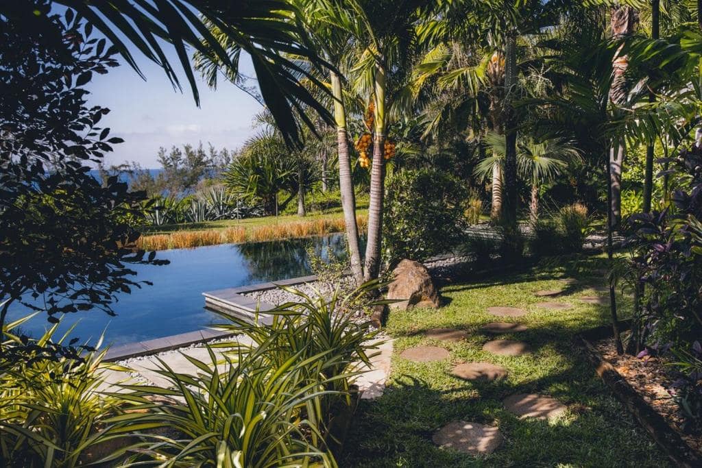 Piscine dans le jardin tropical, palmiers et vue mer au fond · © Domaine du Cap Sauvage