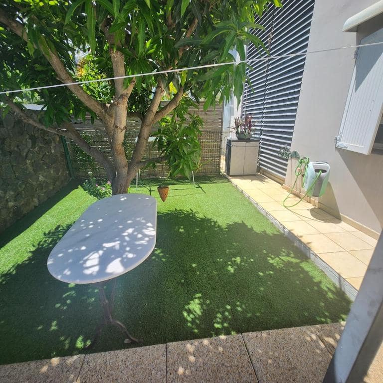 Coin repas sous le manguier, sur pelouse synthétique · © F2 Jardin
