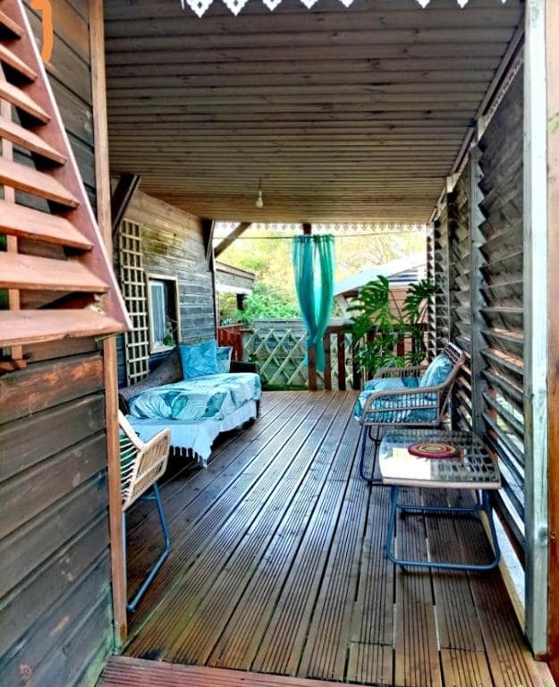 Varangue en bois, banquette bleue et rideau turquoise · © Holi-Wood
