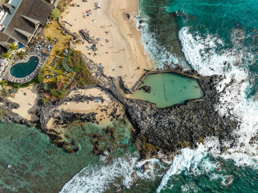 Vue aérienne : piscine, plage et bassin d'océan en contrebas · © Hotel Le Boucan Canot