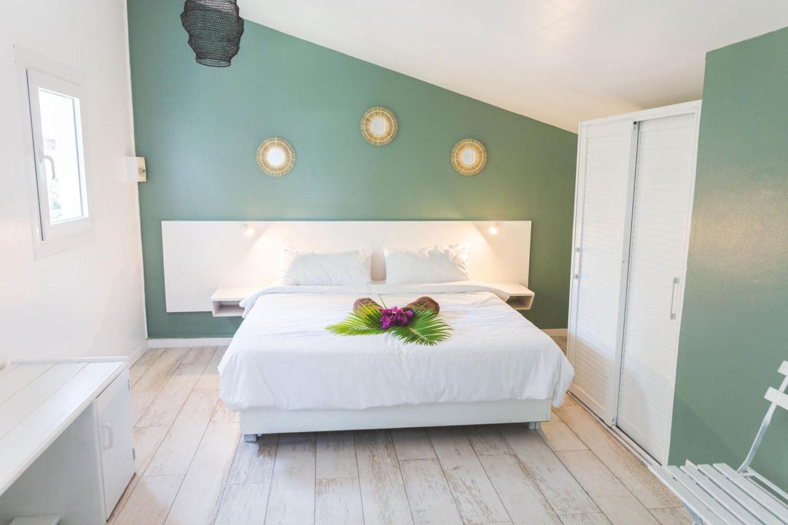 Chambre au mur vert, lit fleuri à l'arrivée · © Ilet du Lagon