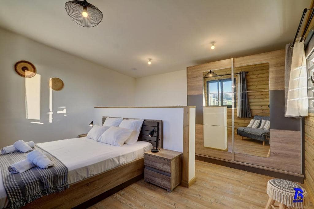 Chambre en bois clair, lit double et dressing miroir · © L'Instant d'Évasion
