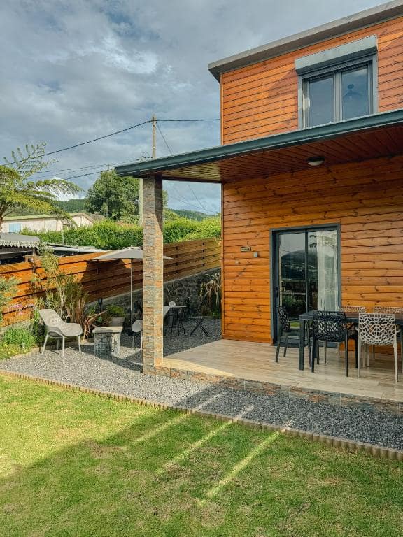Façade en bois du chalet, terrasse et pelouse · © L'Instant d'Évasion