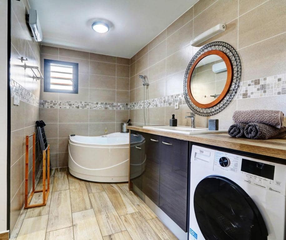 Salle de bains, baignoire d'angle et lave-linge · © L'Instant d'Évasion
