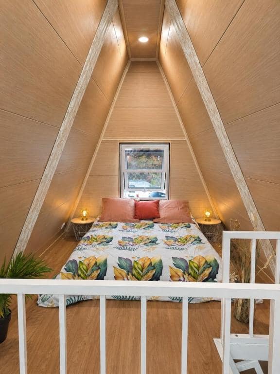Lit en mezzanine sous charpente A-frame, plaid à motif tropical · © Kaz triang