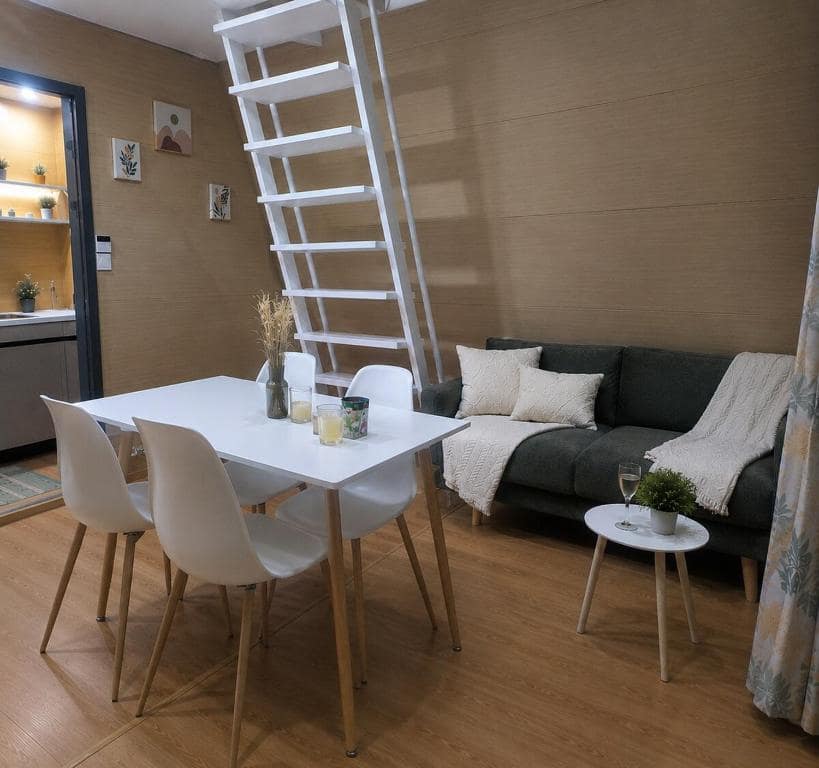Table à manger et canapé, échelle blanche menant à la mezzanine · © Kaz triang