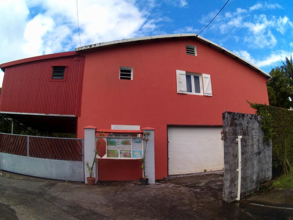 Maison créole peinte en rouge brique vue de la rue · © La baie rose