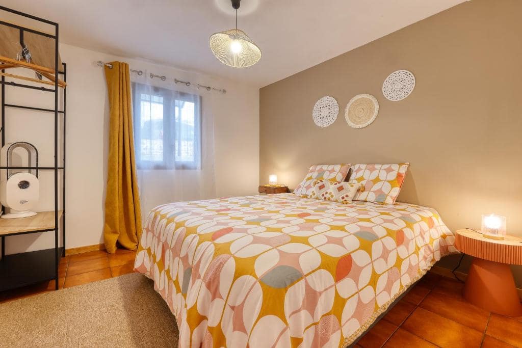 Chambre principale, couvre-lit géométrique jaune, chevet rond · © La Kaz Mamie