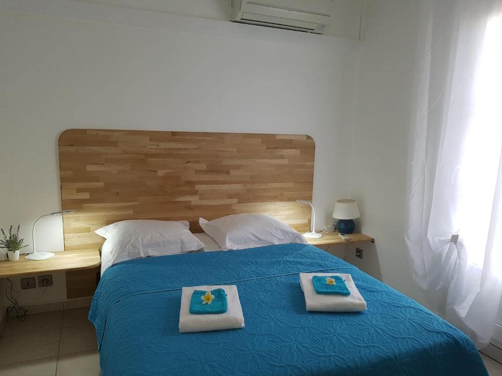 Chambre principale avec tête de lit en bois clair · © La Perle Marine