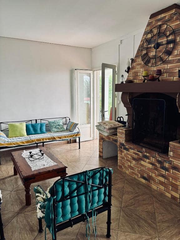 Grand séjour à cheminée brique, banquette et fauteuil vert · © La Salazienne