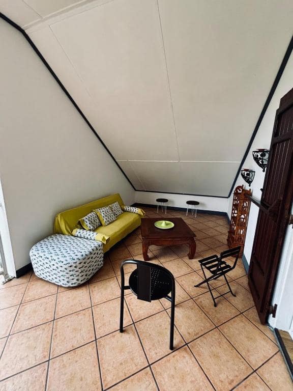 Petit salon mansardé de l'étage, canapé jaune et pouf coordonné · © La Salazienne