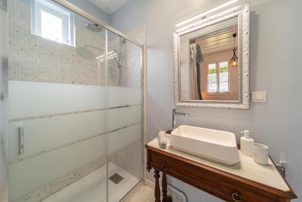 Salle d'eau, douche à l'italienne et grand miroir doré au-dessus de la vasque · © La Villa Blanche