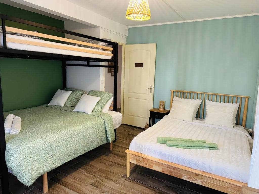 Chambre mixte, lits superposés et lit d'appoint sur mur vert · © LaKaz à Eva