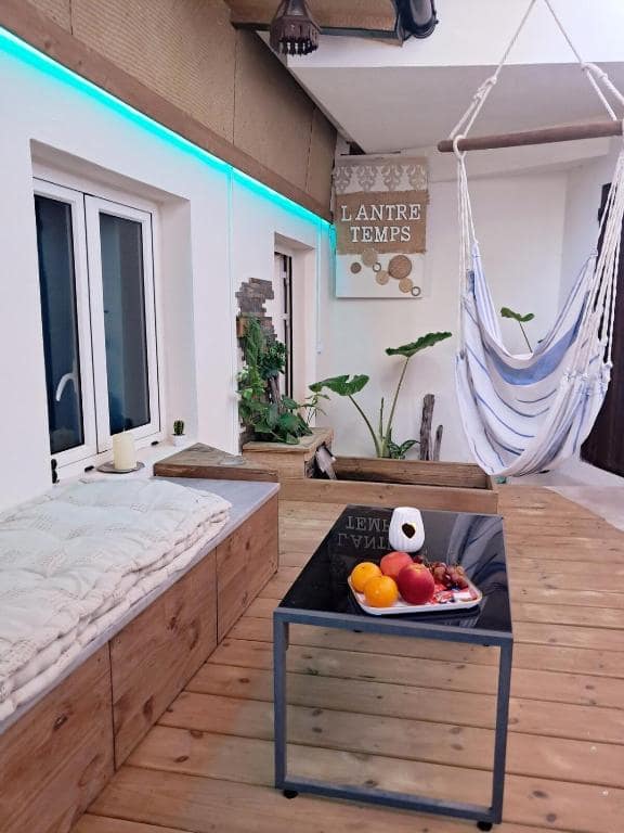 Salon avec banquette bois et hamac suspendu · © l'Antre Temps