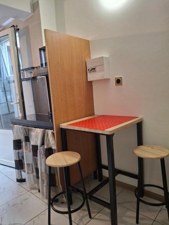 Studio 3 : table haute à plateau rouge et tabourets, coin bar · © Bivouac Maïdo