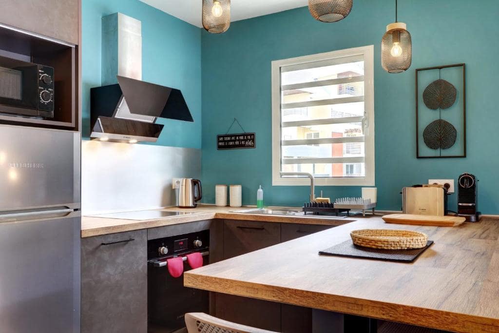 Cuisine avec mur turquoise et machine à café · © Le Céladon