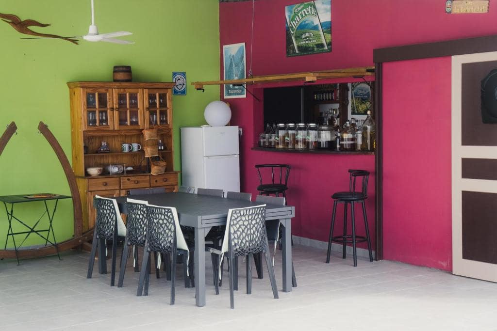 Salon commun aux murs pistache et fuchsia, bar à rhums arrangés · © Le Quindio