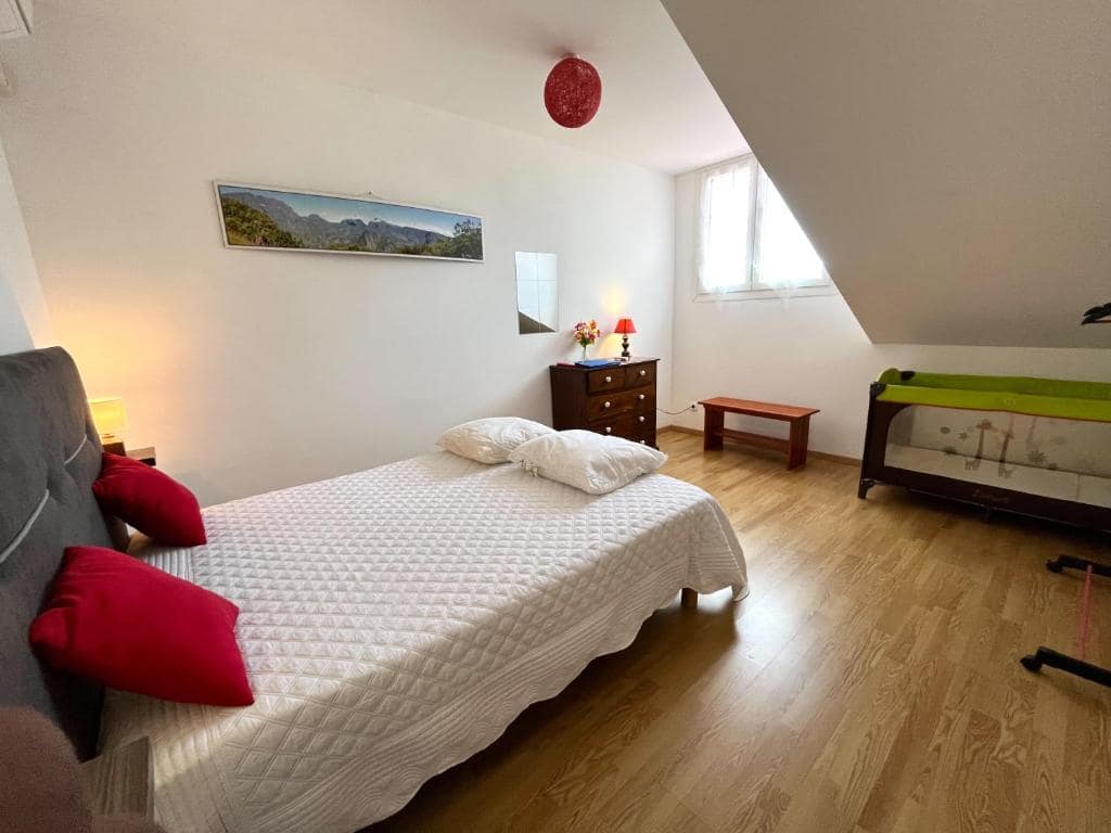 Chambre à l'étage avec canapé rouge d'appoint et lit bébé · © Le Quindio