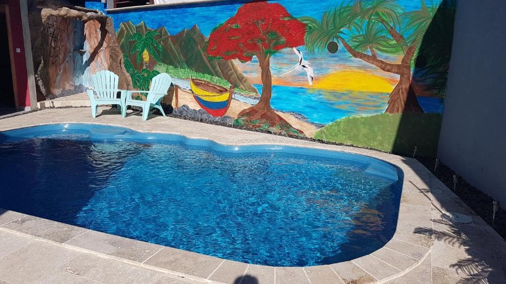 Bassin extérieur devant une grande fresque murale tropicale · © Le Quindio