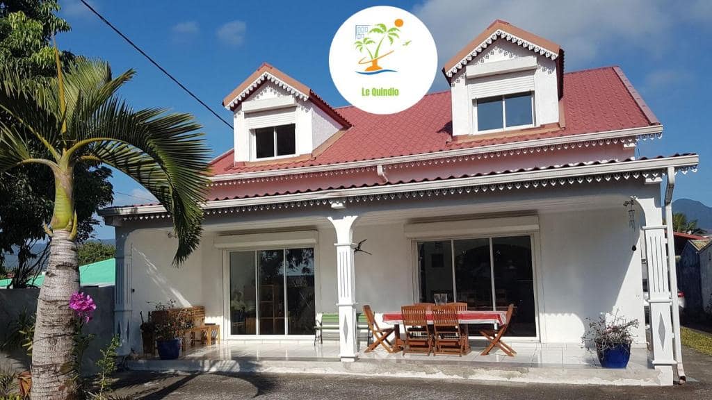 Maison créole blanche à toit rouge et grand palmier · © Le Quindio